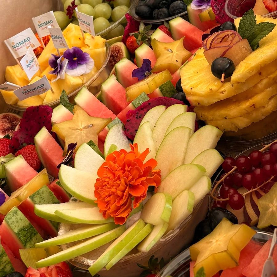 Sliced fruit, berries and edible flowers in a grazing box.
