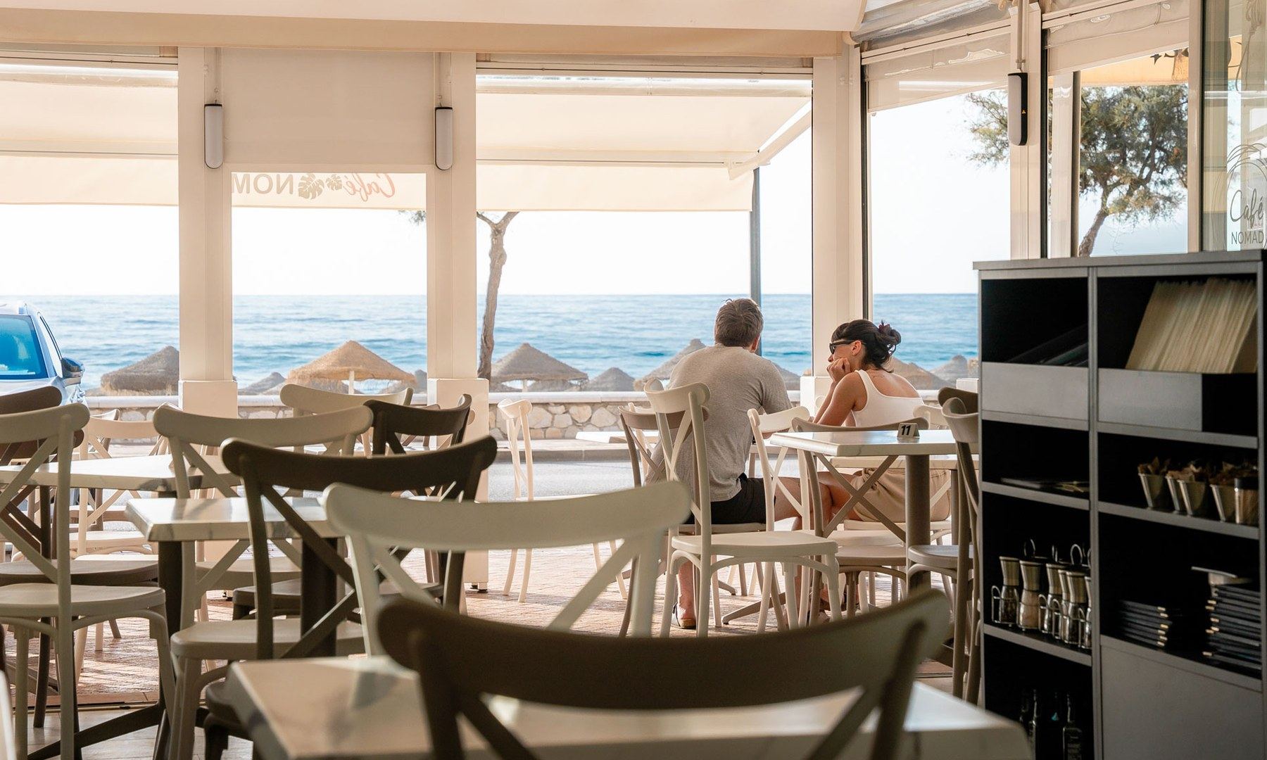 The Café Nomad dining room open to the sea, tables set facing Fuengirola beach.